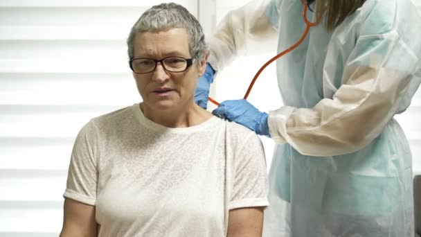女医生用留声机听一位老年病人讲验尸官的症状. — 图库视频影像