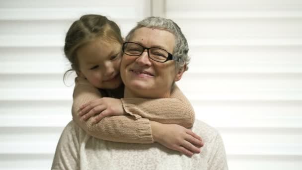 Egy 7-8 éves lány szeretettel öleli meg idős nagyanyját. A nagyi boldog. Családi értékek. — Stock videók