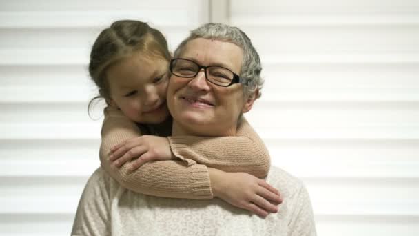 A 7-8 year old girl affectionately hugs her elderly grandmother. Grandma is happy. Family values. — Stockvideo