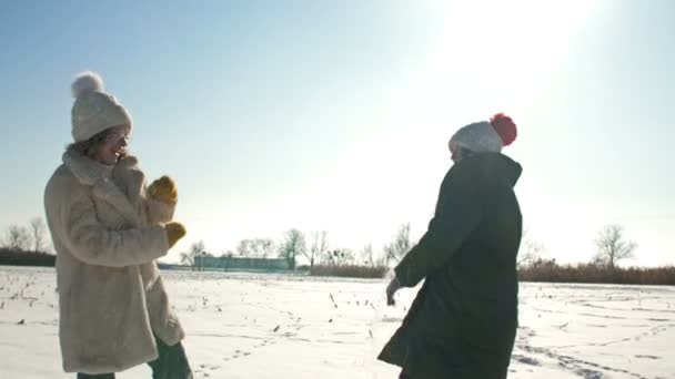 Két lány hógolyózik. Téli séta, napsütéses nap. — Stock videók