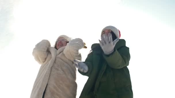 Cute nastolatek dziewczyna i jej starsza siostra lub mama bawią się śniegiem podczas zimowego spaceru. — Wideo stockowe