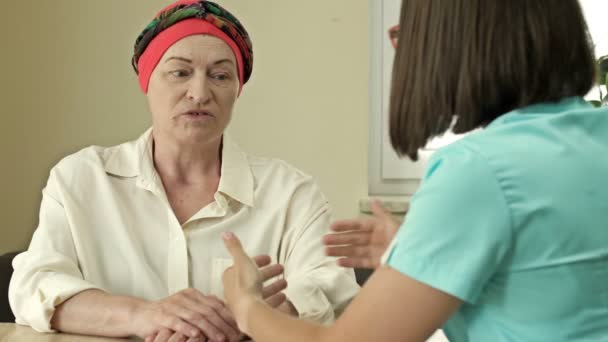Пациентка с раком, носящая платок после химиотерапии, консультируется с онкологом. — стоковое видео