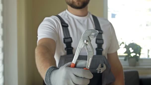 Maître de maison. Jeune homme fort en salopette avec une clé réglable dans ses mains. — Video