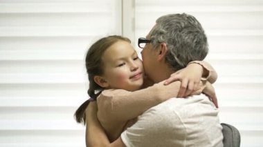 A 7-8 year old girl affectionately hugs her elderly grandmother. Family values.