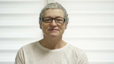 Portrait of an elderly woman after chemotherapy. Hair began to grow back. The woman smiles, hoping for a complete recovery.