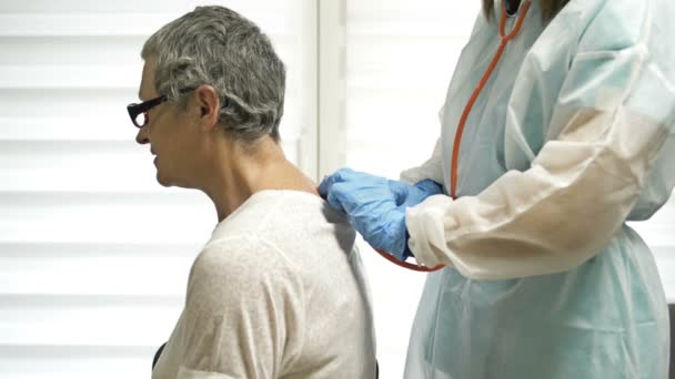 Dokter perempuan mendengarkan dengan fonendoskop kepada pasien lanjut usia dengan gejala-gejala coronavirus. — Stok Video