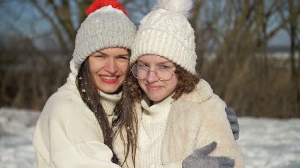 Mujer joven y su hija adolescente se están divirtiendo en un paseo de invierno. Día soleado, vacaciones en familia. — Vídeos de Stock