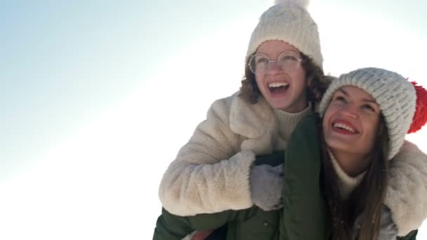 Mujer joven y su hija adolescente se están divirtiendo en un paseo de invierno. Día soleado, vacaciones en familia. — Vídeo de stock