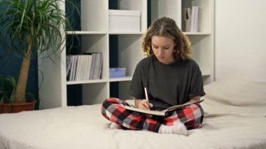 Evdeki yatakta oturup ödev yapan tatlı bir genç kız. Genç ve güzel bir kız bir deftere bir şeyler yazıp düşünür, internetten öğrenir, uzaktan öğrenir, kendini eğitir..