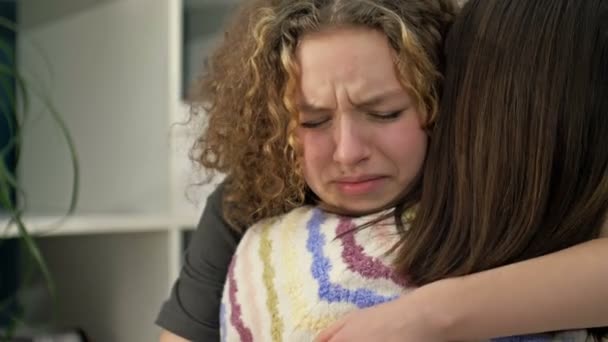 Teenage girl is crying bitterly on the shoulder of her mother or friend. — Stockvideo