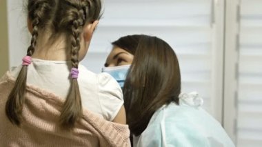 Aşıyı alan okul çağındaki kız. Zorunlu aşı. Çocuğa klinikte omzundan aşı yapılır. Arka plan