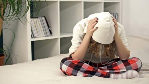 Teenage girl sits alone on the bed and cries, covering her face with her hands. Teenage problems. — Stock Video