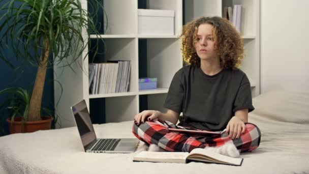 Difficoltà di apprendimento a distanza. Adolescente che fa i compiti seduto sul letto a casa. Non tutto funziona, la ragazza è sconvolta.. — Video Stock