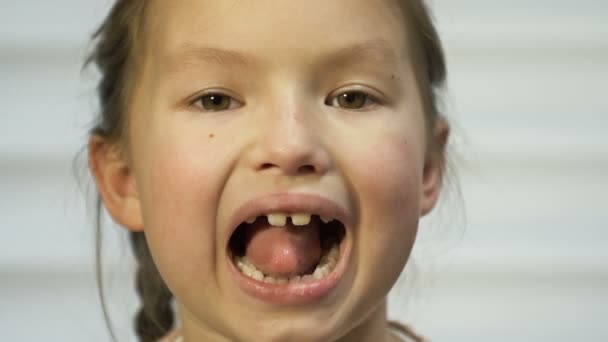 Flicka 7-8 år gammal visar flitigt sin tunga. Kanske vid ett läkarbesök. — Stockvideo