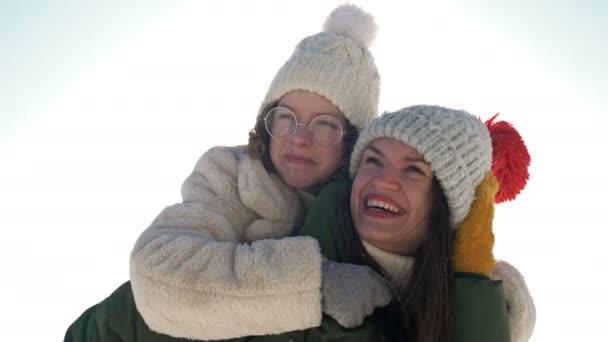 Young woman and her teenage daughter are having fun on a winter walk. Sunny day, family vacation. — Stock videók