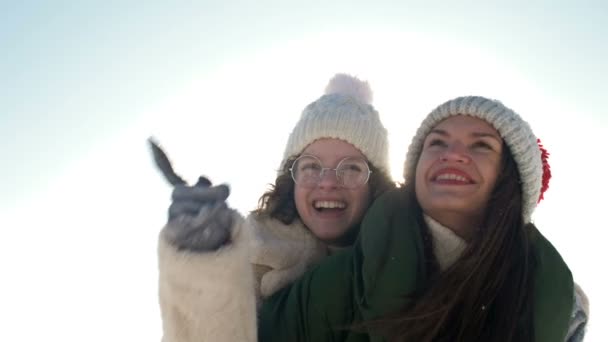 Mujer joven y su hija adolescente se están divirtiendo en un paseo de invierno. Día soleado, vacaciones en familia. — Vídeos de Stock