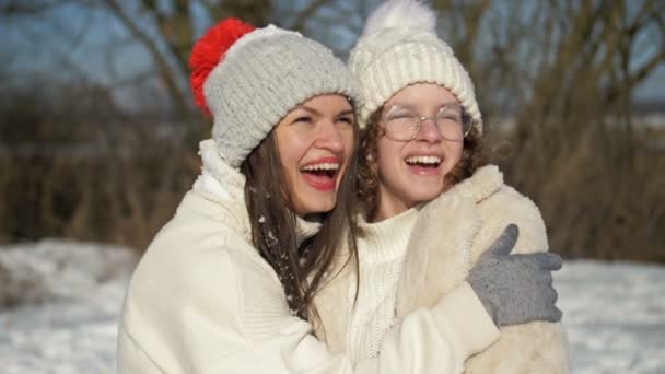 Mujer joven y su hija adolescente se están divirtiendo en un paseo de invierno. Día soleado, vacaciones en familia. — Vídeos de Stock