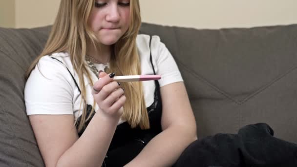 Portré aggódó tinédzser lány ül a kanapén, miközben egy terhességi teszt. — Stock videók