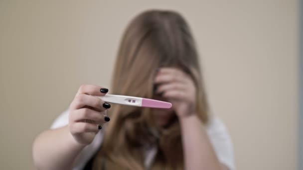 10代の少女は妊娠のためのストリップテストを示しています。2行正の結果だ。10代の妊娠. — ストック動画