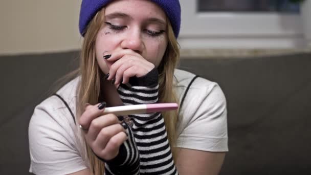 Tonårstjej tittar på resultatet av ett graviditetstest och gråter. Det sociala problemet. — Stockvideo