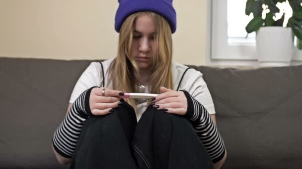 Menina adolescente olha para o resultado de um teste de gravidez e chora. O problema social. — Vídeo de Stock