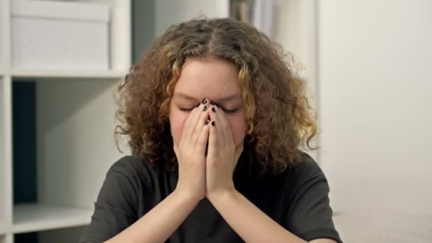 Teenagermädchen sitzt allein und weint und bedeckt ihr Gesicht mit den Händen. Teenagerprobleme. — Stockvideo