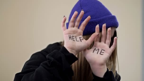 Ragazza adolescente si copre il viso con i palmi delle mani con l'iscrizione HELP ME. — Video Stock