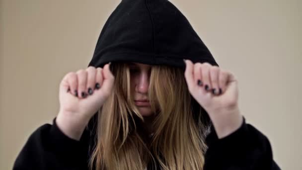 Tiener meisje, bedekt haar gezicht met een kap, toont haar handpalmen met de inscriptie HELP ME. — Stockvideo