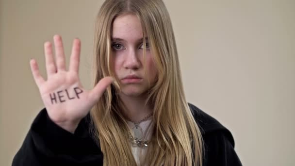 Portrait of a frustrated teenage girl showing her palms with the inscription HELP ME. — Stock Video