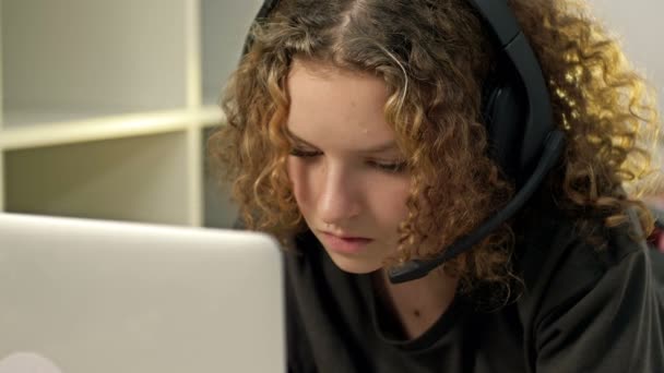 Ragazza adolescente che utilizza il computer portatile e indossa le cuffie. Tecnologie moderne e concetto di tempo libero, istruzione e comunicazione. — Video Stock