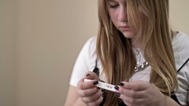 Adolescente mira con miedo a una prueba de embarazo. — Vídeo de stock