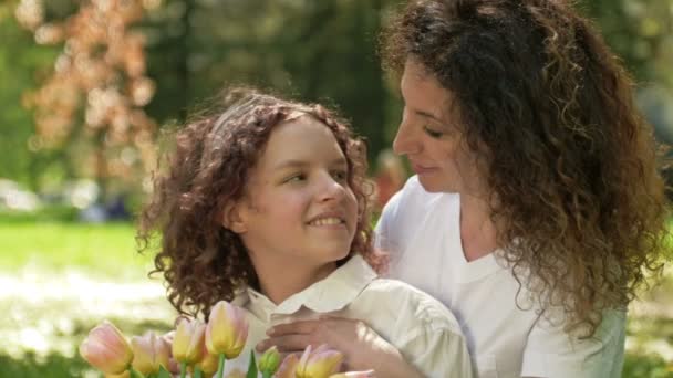 Portrait of a woman with a bouquet of tulips hugging her teenage daughter. Mothers Day. — Stock Video