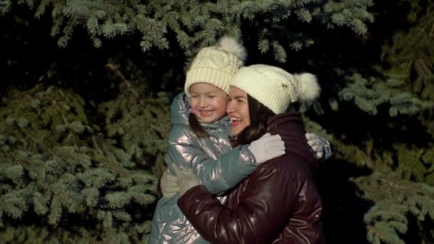 Procházka v zimním lese. Dívka, které je 7-8 let, jemně objímá svou matku. Mladá žena poukazuje na něco zajímavého pro svou dceru. Rodinná dovolená.