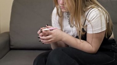 Genç kız hamilelik testine heyecanlı ve şaşkın bir şekilde bakıyor. O, sonuçtan şok oldu. Genç yaşta hamilelik sorunları.