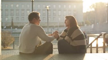 Rıhtımda romantik bir buluşma. Bir çift aşık şehrin sehpasında oturur ve neşeyle iletişim kurar, erkek kızın elini tutar..