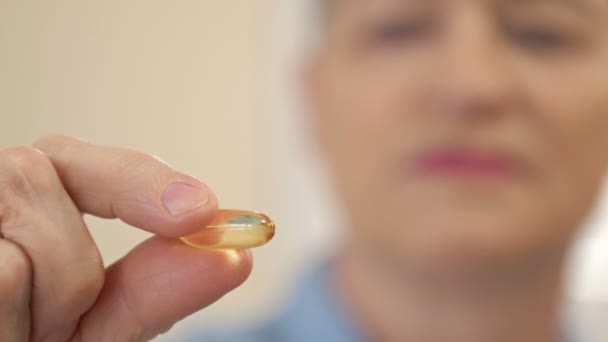 手里拿着鱼油胶囊的女人鱼油胶囊作为一种含omega-3和维生素a的膳食补充剂，在保健方面是很高的. — 图库视频影像
