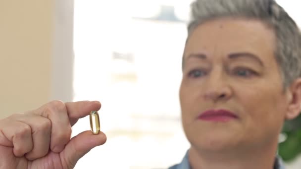 Γυναίκα που κρατάει την κάψουλα με το ιχθυέλαιο στο χέρι. κάψουλες ιχθυελαίου ως συμπλήρωμα διατροφής που περιέχουν ωμέγα-3 και βιταμίνη Α είναι υψηλή για την υγειονομική περίθαλψη. — Αρχείο Βίντεο