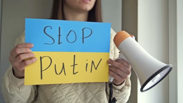 Donna sta tenendo un poster con l'immagine della bandiera ucraina, che dice STOP PUTIN. — Video Stock