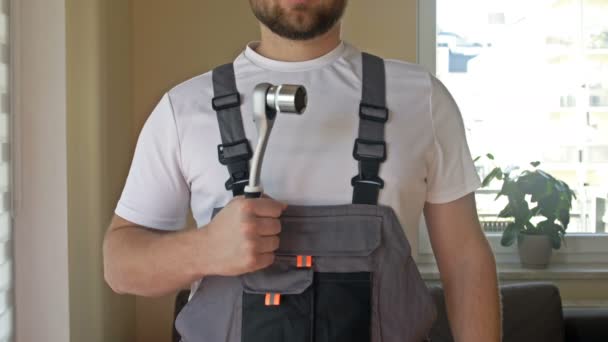 Home master or service worker. A young strong man in overalls with an adjustable wrench in his hands. — Stock Video