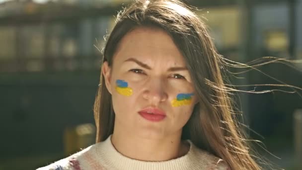 Retrato de una mujer con rayas amarillas y azules pintadas en sus mejillas. Bandera de Ucrania. Guerra entre Ucrania y Rusia. — Vídeos de Stock