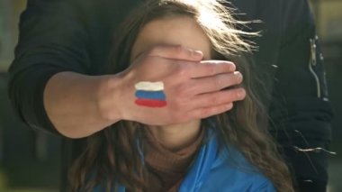 Rus bayrağının görüntüsüyle el ele tutuşan insanlar, Ukrayna bayrağı taşıyan küçük bir kızın yüzünü kabaca kapatıyor. Ukrayna 'ya özgürlük. Rus saldırganlığı.