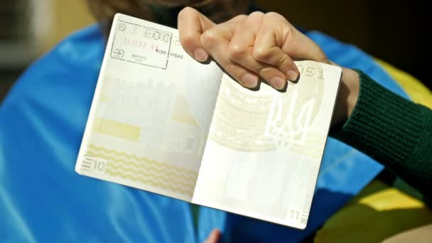 Mulher com uma bandeira ucraniana nos ombros tem um passaporte ucraniano com um visto polonês. Guerra na Ucrânia. Refugiados. — Vídeo de Stock