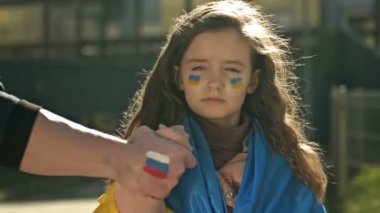 Rus bayrağının görüntüsüyle el ele tutuşan insanlar, kabaca Ukrayna bayrağıyla küçük bir kızın elini çekiyorlar. Rusya Ukrayna 'ya hain saldırı.