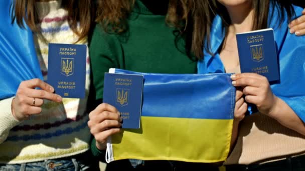 우크라이나 국기로 뒤덮인 세 명의 여성 이 포옹하고 있다. 우크라이나 여권을 들고 있다. 우크라이나 에서의 러시아 침략을 막으라. — 비디오