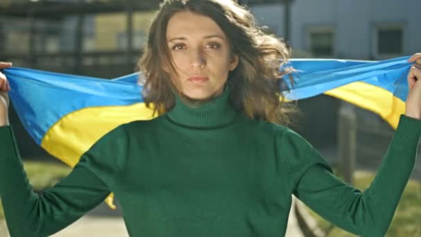 Портрет жінки з українським прапором на його плечах. Протест проти війни в Україні та російської агресії. — стокове відео