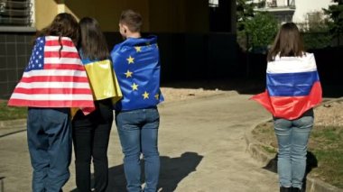 Ukrayna, ABD ve AB bayraklarıyla kucaklaşan bir grup insan. Dayanışma ve desteğin sembolü. Rus bayrağı taşıyan bir kadın tek başına duruyor..
