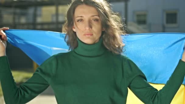 Porträt einer Frau mit einer ukrainischen Flagge auf den Schultern. Protest gegen den Krieg in der Ukraine und die russische Aggression. — Stockvideo