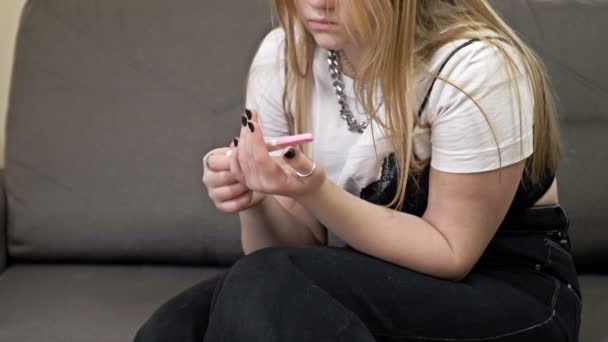 Adolescente mira con miedo a una prueba de embarazo. — Vídeo de stock