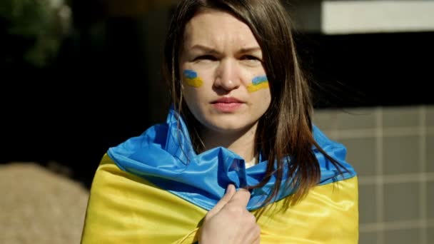 Porträt einer Frau mit einer ukrainischen Flagge auf den Schultern. Protest gegen den Krieg in der Ukraine und die russische Aggression. — Stockvideo