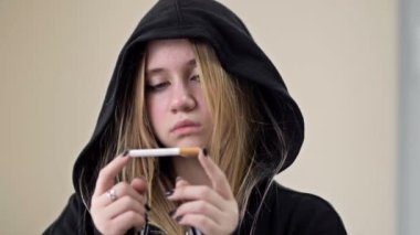 Genç kız sigarasını kırıyor. Sigara karşıtı protesto. Zararlı bir bağımlılığa son verme arzusu.